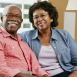 an old African American couple smiling with joy after finding a seemingly perfect caregiver just nearby