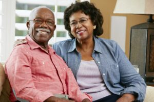 an old African American couple smiling with joy after finding a seemingly perfect caregiver just nearby